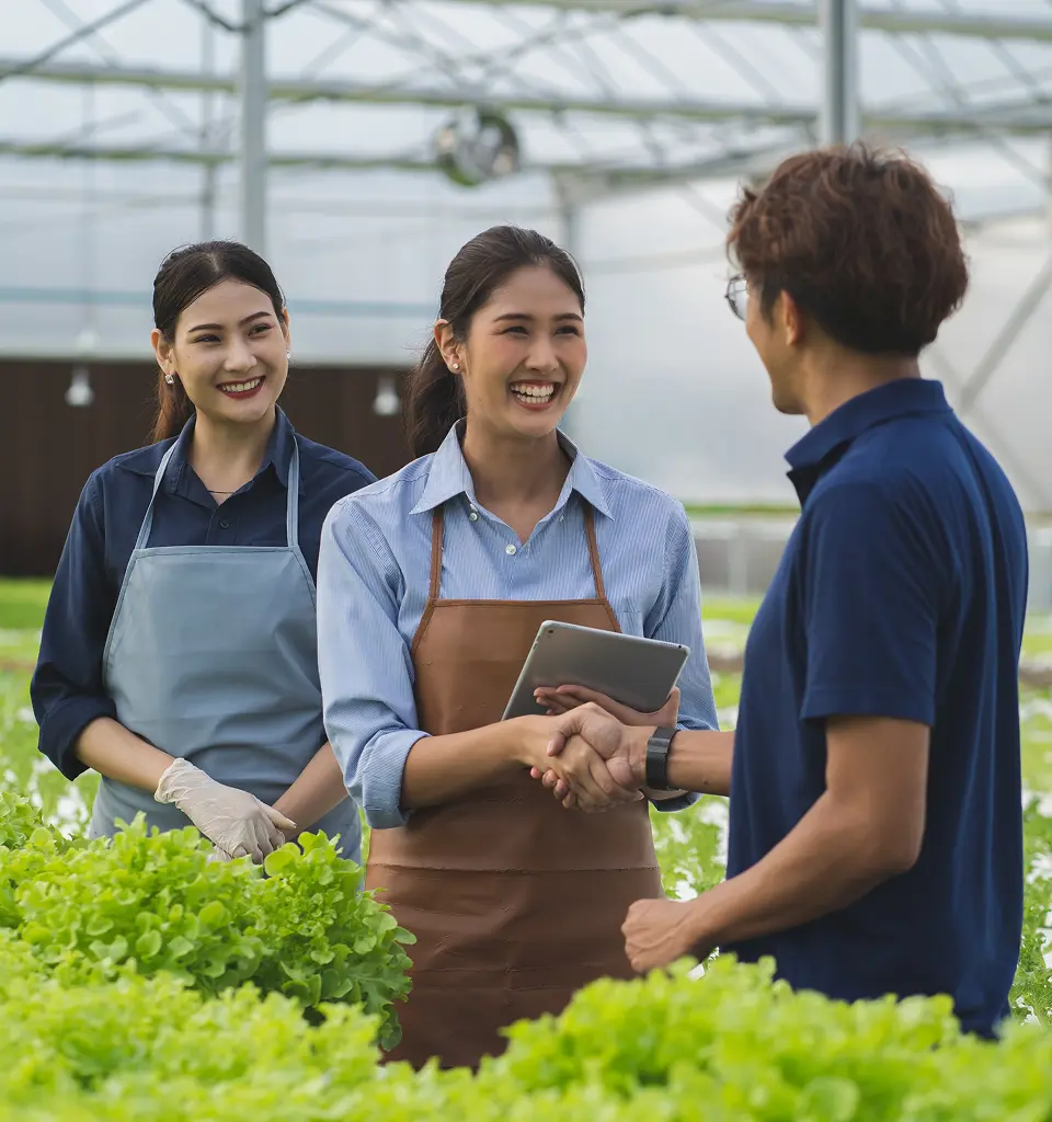 Dua wanita dan satu pria ditengah kebun sedang berjabat tangan